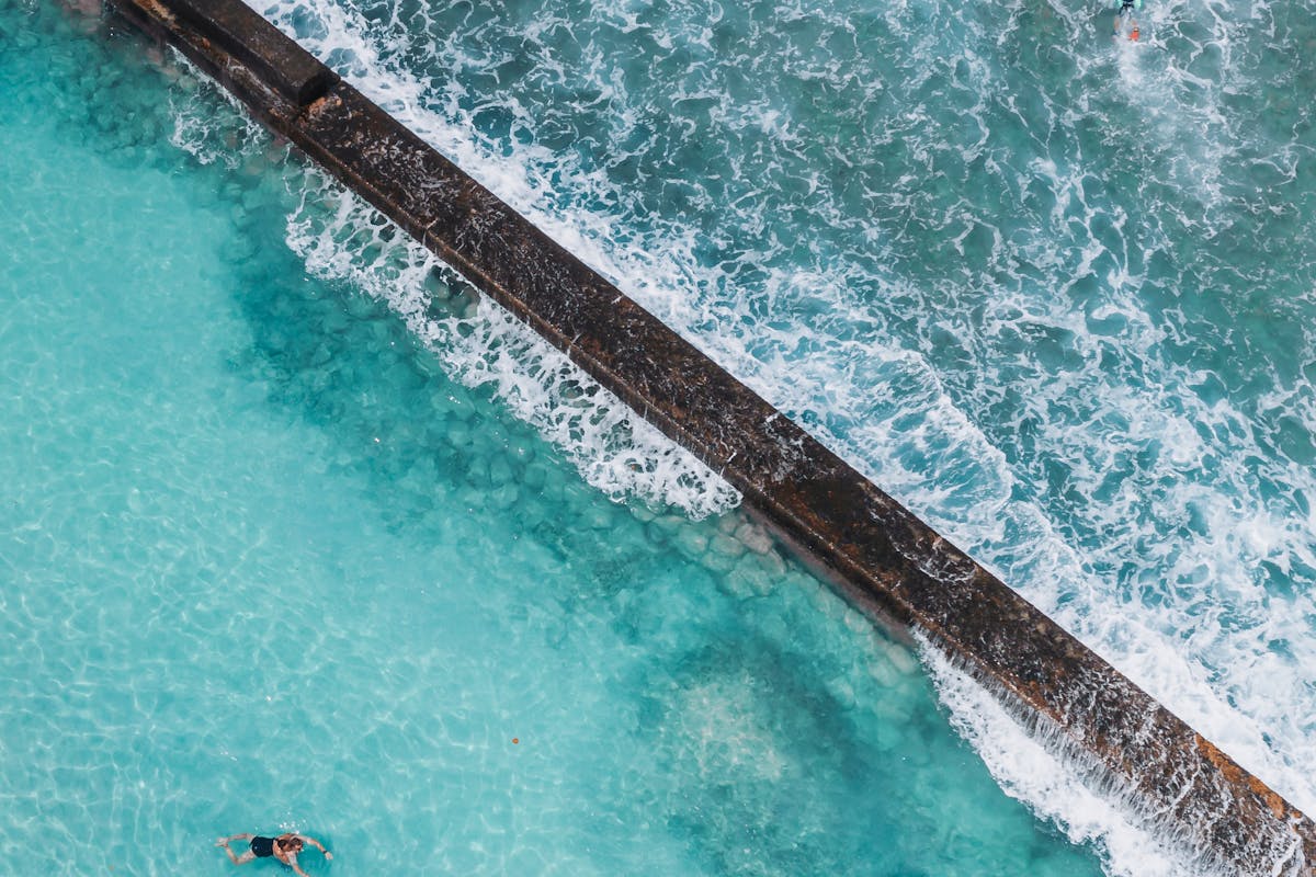 Stunning aerial view of an ocean pool in Hawaii with clear blue waters and crashing waves