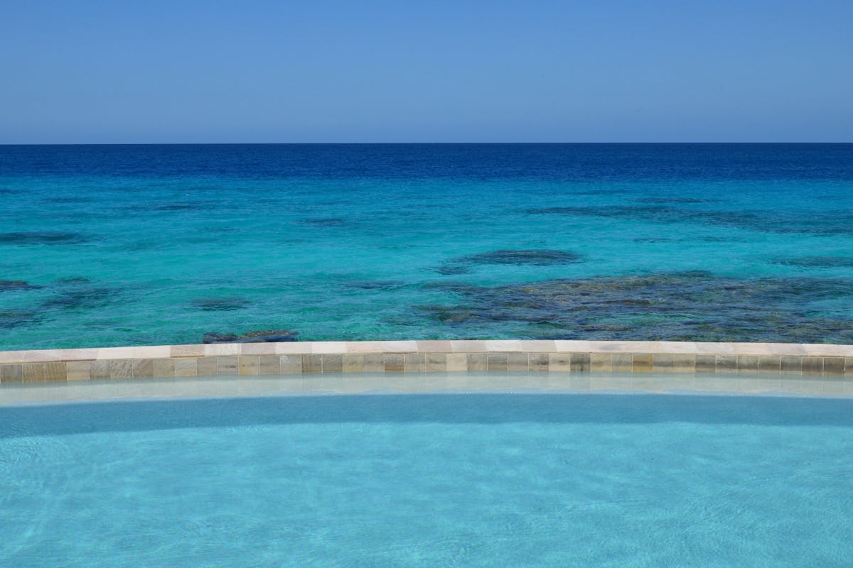 Infinity pool with breathtaking turquoise ocean view on a clear sunny day
