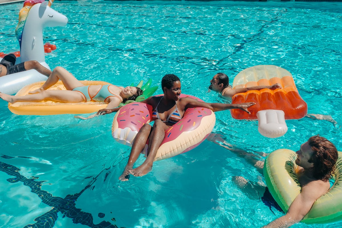 Fun pool party with friends enjoying colorful floats in tropical swimming pool